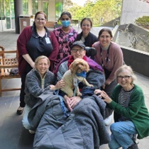 5 West patient Richard and his family receive a visit from Lort Smith Pet Therapy dog Molly and her owner Sophie, in the ONJ Centre Wellness Garden. They are joined by nursing and admin staff from 5 West.